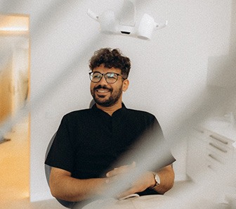 Patient with black glasses smiling in treatment chair