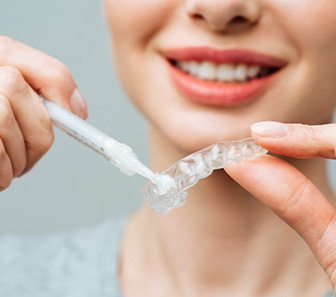A woman using an at-home teeth whitening tray