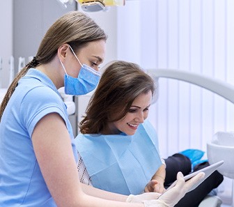 A smiling woman paying the cost of her dental care