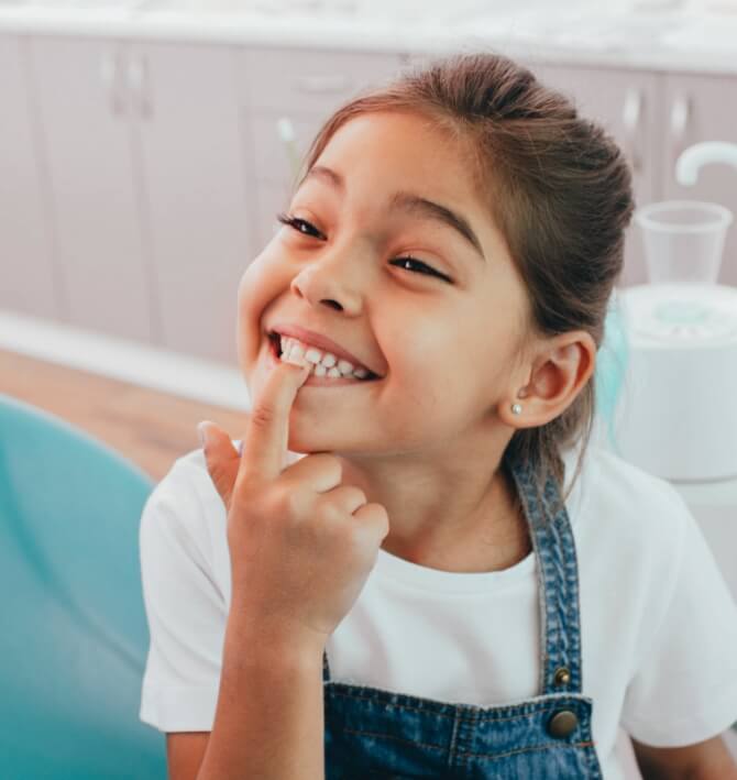 Child pointing to smile during children's dentistry visit