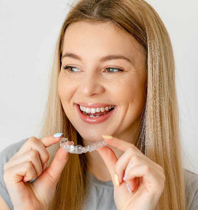 Smiling woman holding aligner for ClearCorrect in McKinney
