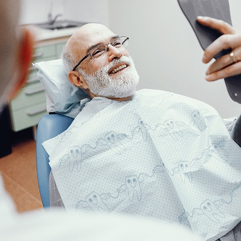 a patient checking his dentures with a mirror