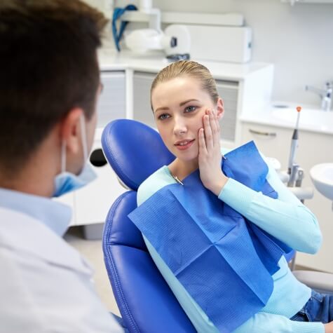 Woman in need of emergency dentistry holding jaw