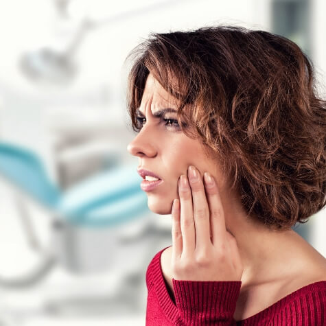 Woman holding jaw before emergency dentistry