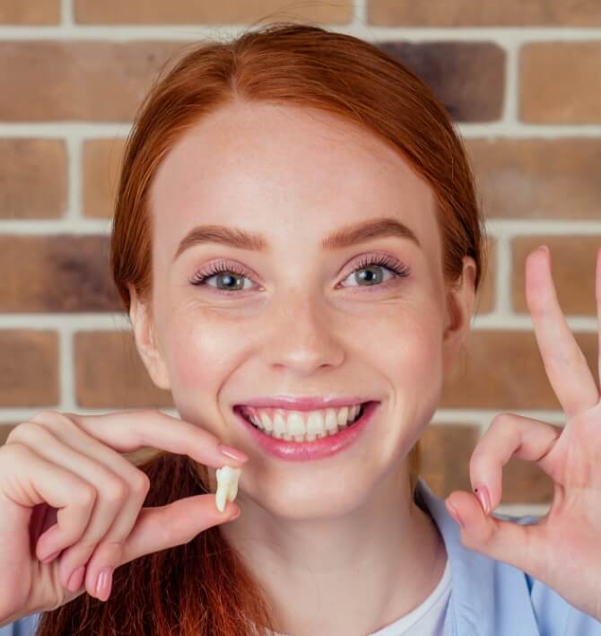 Woman holding up wisdom tooth after extraction