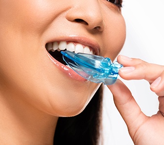 Woman placing blue nightguard into her mouth