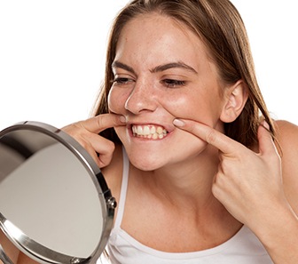 Patient in McKinney checking dental implants in mirror