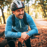 Smiling man riding his bike in a forest