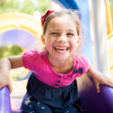 Young girl in pink shirt laughing on outdoor playground