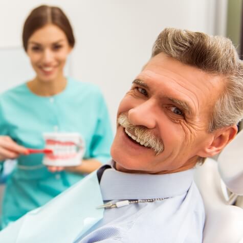 Older man with dentures smiling during dental visit