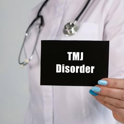 Doctor holding sign that says “TMJ disorder”