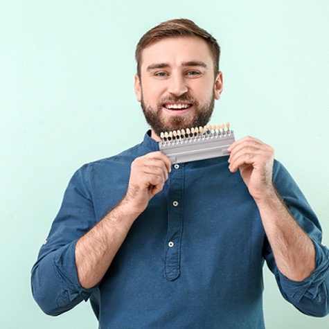 man smiling and holding veneer replicas in McKinney