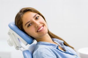 Happy, smiling dental patient in treatment chair 