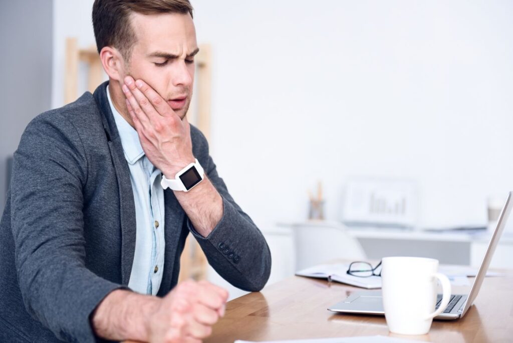 A man with jaw pain sitting at a desk